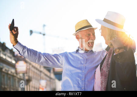 Turismo e tecnologia. Viaggiare coppia senior tenendo selfie insieme contro sightseeing sfondo. Foto Stock