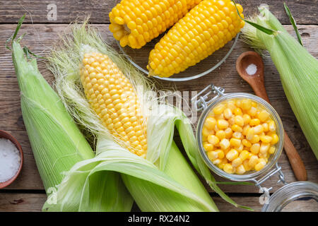 Conserve di mais dolce in un barattolo di vetro, fresco e grano cotto su pannocchie, sale. Vista dall'alto. Foto Stock