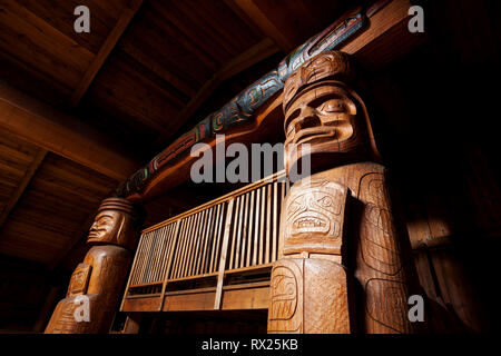 Due grandi montanti d'angolo mettono in evidenza creste e disegni relativi alla gente delle prime nazioni di Wuikinuxv nella loro bighouse. Oweekeno, Rivers Inlet, British Columbia Central Coast, Canada. Foto Stock