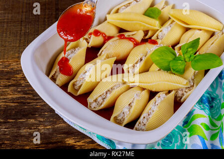 Ripiene di formaggio jumbo gusci di pasta con salsa servita con impostato su bianco Foto Stock