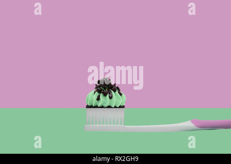 Spazzolino da denti con tortine su due colori rosa e verde, stile minimal. Foto Stock