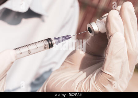 Medico mano azienda flaconcini medicazione e ago di iniezione. Medico di prelevare un farmaco in siringa. Foto Stock