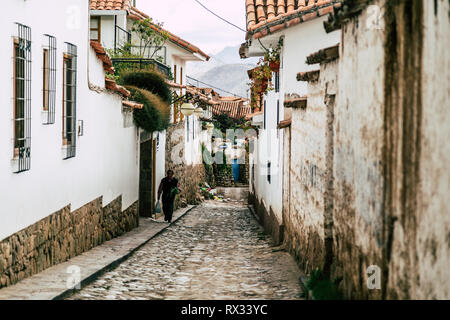 Scena di strada di una tradizionale strada di ciottoli e case bianche (Cusco, Perù). Foto Stock