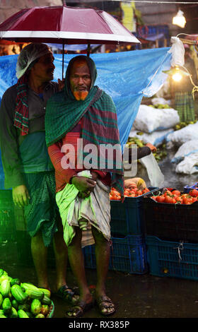 Gli uomini del Bangladesh sotto il loro ombrello a Karwan bazar di Dhaka. Foto Stock