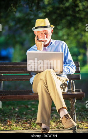 Senior uomo utilizzando computer portatile a riposo nel parco all'aperto Foto Stock