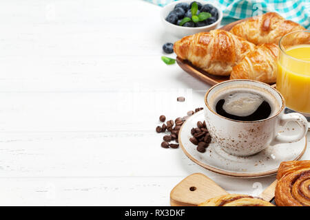 Caffè, cornetti, succo di arancia, panini alla cannella e le bacche di prima colazione. Su un tavolo di legno. Copia con spazio per il testo Foto Stock