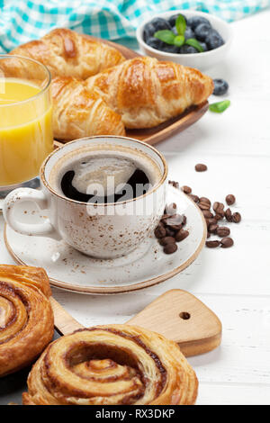 Caffè, cornetti, succo di arancia, panini alla cannella e le bacche di prima colazione. Sul tavolo di legno Foto Stock