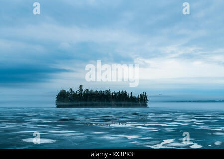 Riscaldare aria sovrastante si mescola con l'aria fredda immediatamente su ghiaccio in ritirata causando una misteriosa nebbia sul Lago dei due fiumi, Algonquin Provincial Park, Ontario, Canada Foto Stock