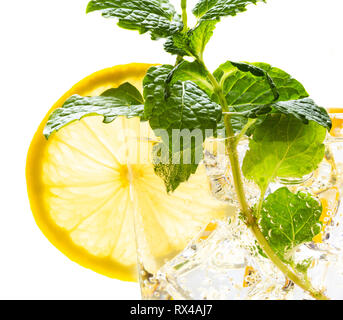 Macro shot di limonata in vetro con limoni,menta e cubetti di ghiaccio isoalted su bianco Foto Stock