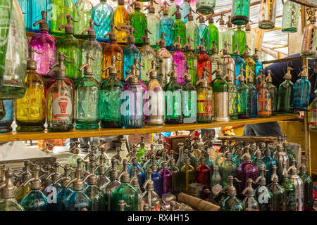 Close up di righe di vetro colorato di soda antichi bottiglie allineate in un mercato di San Telmo, Buenos Aires, Argentina Foto Stock