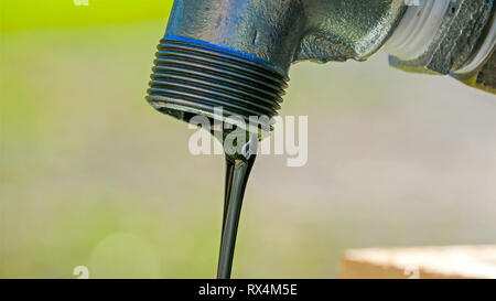 Il nero fluido che fuoriesce dal rubinetto. È interno al tubo del rubinetto Foto Stock
