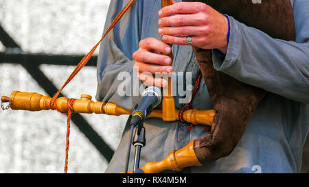 Suonare il flauto con altri strumenti sul suo collo. Durante la riproduzione il flauto l uomo ha altri strumenti appeso sul suo corpo sono stru in legno Foto Stock