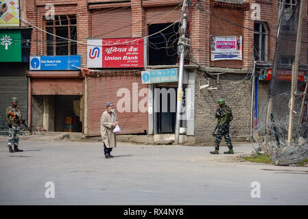 Un vecchio uomo visto a piedi passato paramilitari indiano troopers guardia durante le restrizioni nell'area del centro cittadino di Srinagar. Le autorità impongono delle restrizioni in parti di Srinagar Kashmir per impedire la protesta chiamato da una resistenza comune Leadership (JRL) contro la detenzione di Jammu e Kashmir Liberation Front presidente Yasin Malik e l' arresto del gruppo Jamaat-e-Islamia quadri. Foto Stock