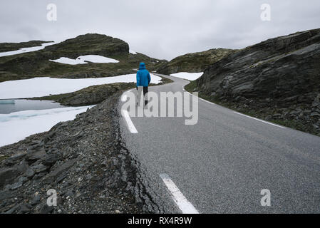 Norwegian itinerario panoramico Aurlandsfjellet. Un ragazzo in una giacca blu che cammina per le strade di montagna Bjorgavegen in Norvegia Foto Stock