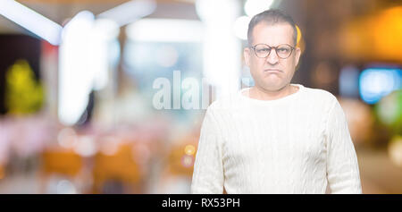 La mezza età uomo arabo con gli occhiali su sfondo isolato scettico e nervoso, accigliata sconvolto a causa del problema. Persona negativa. Foto Stock