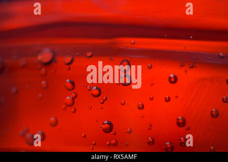 Diverse le bolle in un olio rosso liquido, close-up Foto Stock