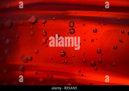 Diverse le bolle in un olio rosso liquido, close-up Foto Stock