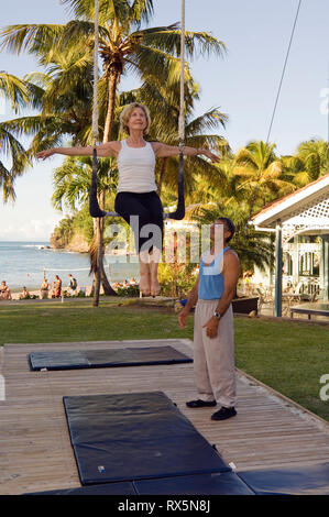 Donna seduta su trapezio dal trainer in posizione di parcheggio Foto Stock