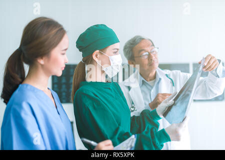 Medici guardando a raggi x in un ospedale .controllo petto x ray film al ward con infermiera e medico donna chirurgo. Foto Stock