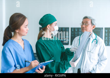 Medici guardando a raggi x in un ospedale .controllo petto x ray film al ward con infermiera e medico donna chirurgo. Foto Stock