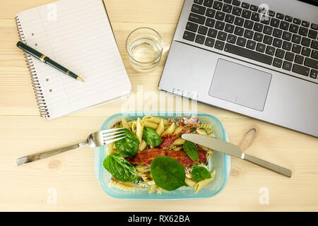 Un pranzo veloce. Scatola di pranzo nella parte anteriore del computer portatile. Concetto di lavoro straordinario, ritardata e stress sul lavoro. Foto Stock