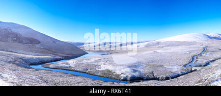 Elan Valley in Galles mostra Afon Elan fiume che scorre attraverso un panorama innevato di una scena invernale delle montagne e il cielo blu. Foto Stock