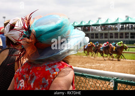 Kentucky Derby corsa di cavalli a Louisville, Stati Uniti d'America - cavalli passando vicino al pubblico che frequentano il Derby con una donna in una grande voglia di hat Foto Stock