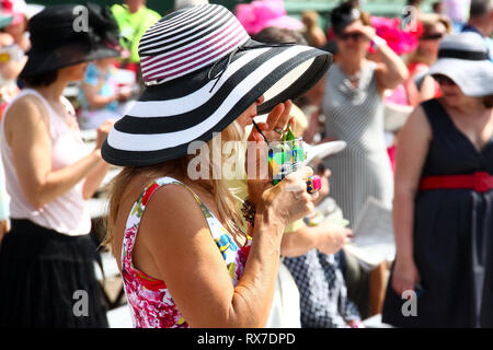 Kentucky Derby corsa di cavalli a Louisville, Stati Uniti d'America - una donna in un fantastico hat beve un Mint Julep alla Derby - Moda Foto Stock