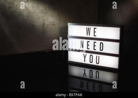 Abbiamo bisogno di voi messaggio di assunzione su una scatola di luce in un cinema moody sfondo Foto Stock