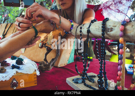 Una donna in casa di vendita gioielli artigianali da un mercato in stallo presso un festival hippy Foto Stock