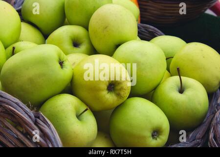 Close up di gustose mele verdi in un cesto di vimini per la vendita in un mercato agricolo Foto Stock