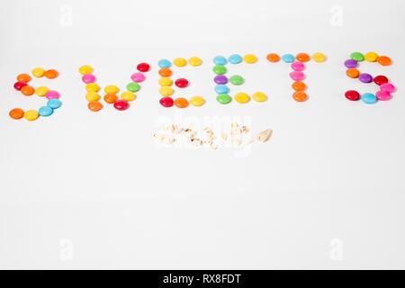 Iscrizione dolci fatti dal dolce colorato di caramelle e la carie dei denti nella parte anteriore - pulire i denti con attenzione - visita dal dentista. Foto Stock