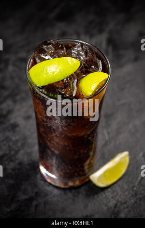 Fresche fatte Cuba Libre marrone con rum, cola e limone su sfondo nero Foto Stock