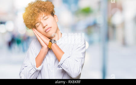 Bel giovane uomo d affari con capelli Afro indossa maglietta elegante dormire stanchi di sognare e in posa con le mani insieme mentre sorridente con gli occhi chiusi Foto Stock