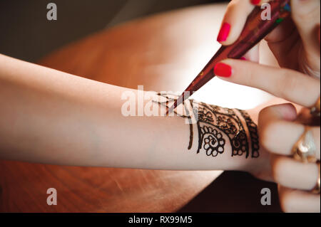 Processo di disegno di henna menhdi ornamento sulla donna di mano Foto Stock