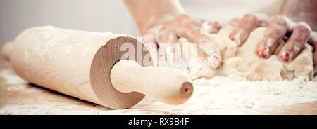Donna che indossa grembiule bianco gli impasti utilizzando mattarello close-up mani femminili rendendo la cottura di cottura di torte torte. Cuocere al lavoro o casalinga nella ki Foto Stock