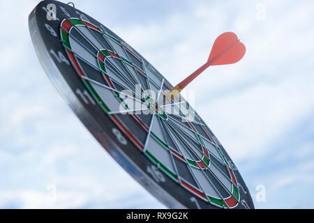 Rosso freccia dart di colpire nel target center di dartboard concorso marketing concetto, su sfondo cielo Foto Stock