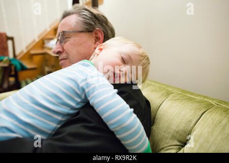 Nonno che trasportano carino nipote dorme sulla spalla a casa Foto Stock