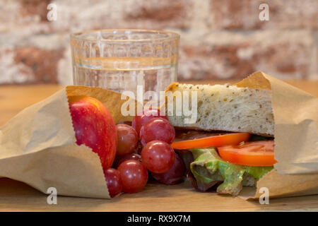 Alternativa libera di plastica sano pranzo al sacco cibo utilizzando autentici vero cibo fatto in casa in borse di carta marroni. Pomodoro, pane casereccio, uva, Apple Foto Stock