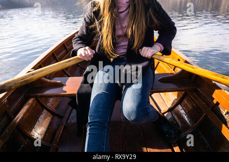 Giovane donna con paletta su una barca di legno - Lago di Bled Slovenia il canottaggio su barche in legno Foto Stock