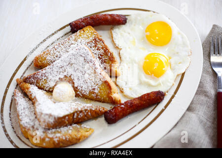 Angolo di alta vista di uova fritte con pane e salsicce servita nella piastra sulla tabella Foto Stock