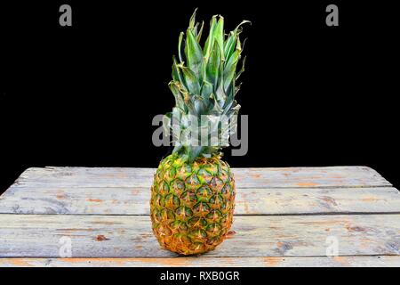 Ananas fresco isolata contro uno sfondo nero ananas sul bianco backgroud in legno. Copia dello spazio. Foto Stock