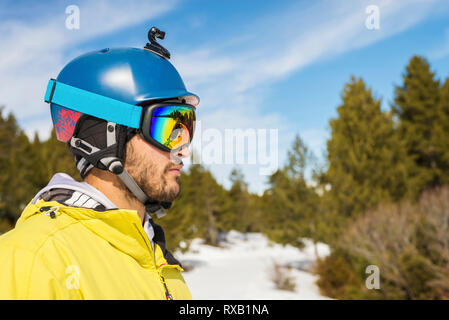 Vista laterale di uomo che indossa il casco sport mentre in piedi contro il cielo durante il periodo invernale Foto Stock