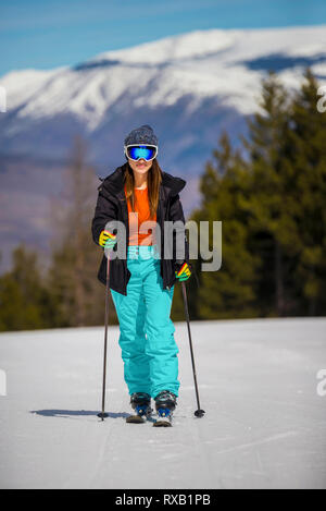 Donna con cieli passeggiate sulla neve coperto campo contro la montagna in foresta Foto Stock