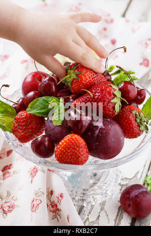 Baby mano richiede un fragole mature dal piatto. Estate sani snack. Foto Stock