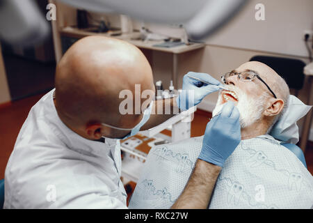 Il vecchio uomo seduto in studio dentistico Foto Stock