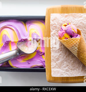 Multicolore di rosa, blu e viola sapore di gomma di gelato in forma metallica accanto ad una pronta cono di cui è stato eseguito il rip Foto Stock