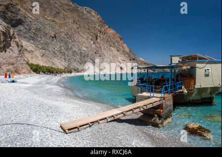 Una taverna costruita su rocce nel mare a Sweetwater Beach, tra Hora Sfakion e Loutro sulla costa meridionale di Creta. Foto Stock