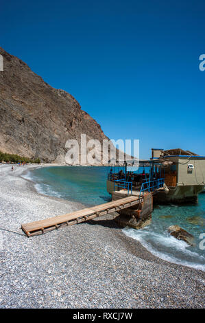 Una taverna costruita su rocce nel mare a Sweetwater Beach, tra Hora Sfakion e Loutro sulla costa meridionale di Creta. Foto Stock