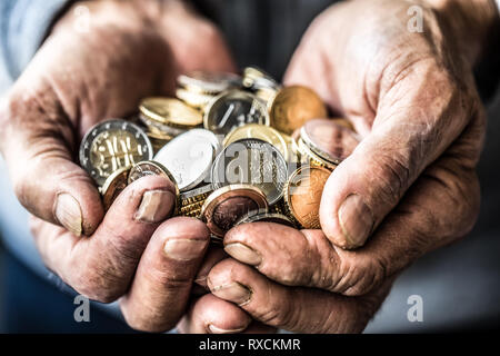 Titolare di pensione o di rendita uomo tenendo in mano delle monete in euro. Il tema delle pensioni basse. Foto Stock